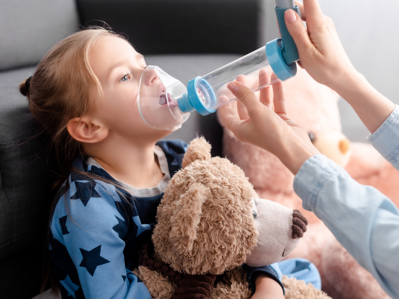 Parent administeing inhaler to child using a spacer